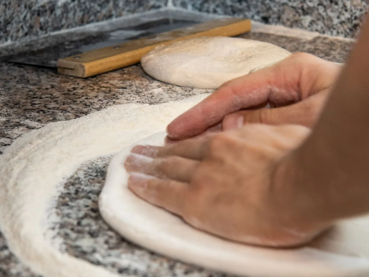Ein Bäcker formt Teig auf einer bemehlten Arbeitsfläche